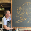 designer greg morris holding a large carving of a bear artwork in his art studio.