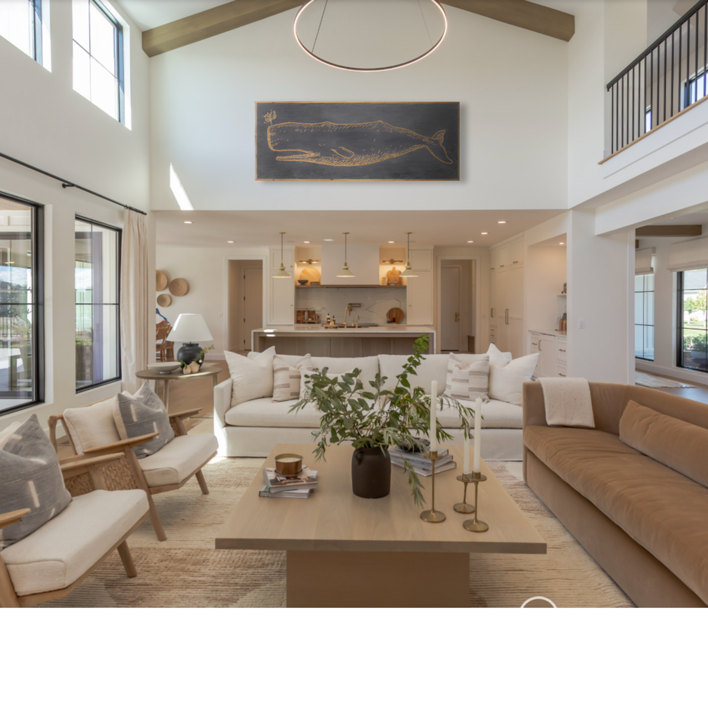 Modern living room with beige sofa, white chairs, and a coffee table featuring a 71" carved whale artwork over the livingroom