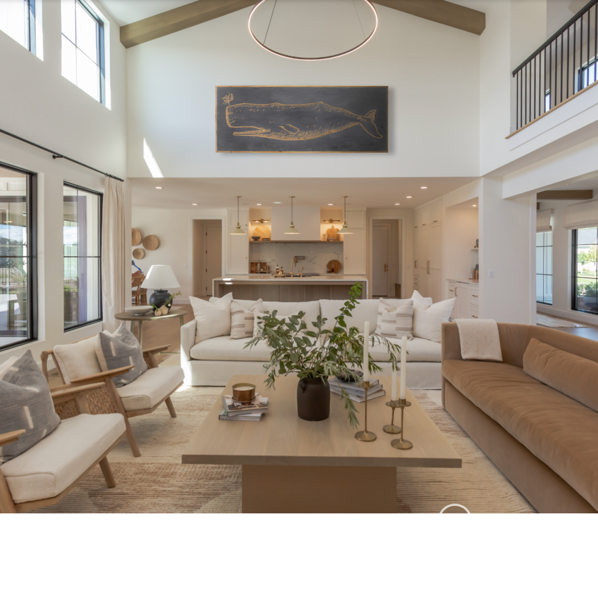 Modern living room with beige sofa, white chairs, and a coffee table featuring a 71" carved whale artwork over the livingroom