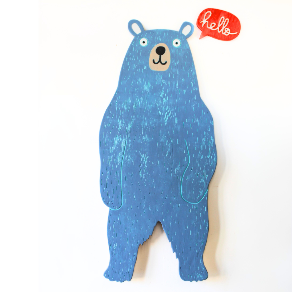 A blue bear-shaped wall hanging or decorative plaque with a textured wood-like finish, shown against a plain white background. A small red speech bubble near the top right contains the word 'hello' in white script.