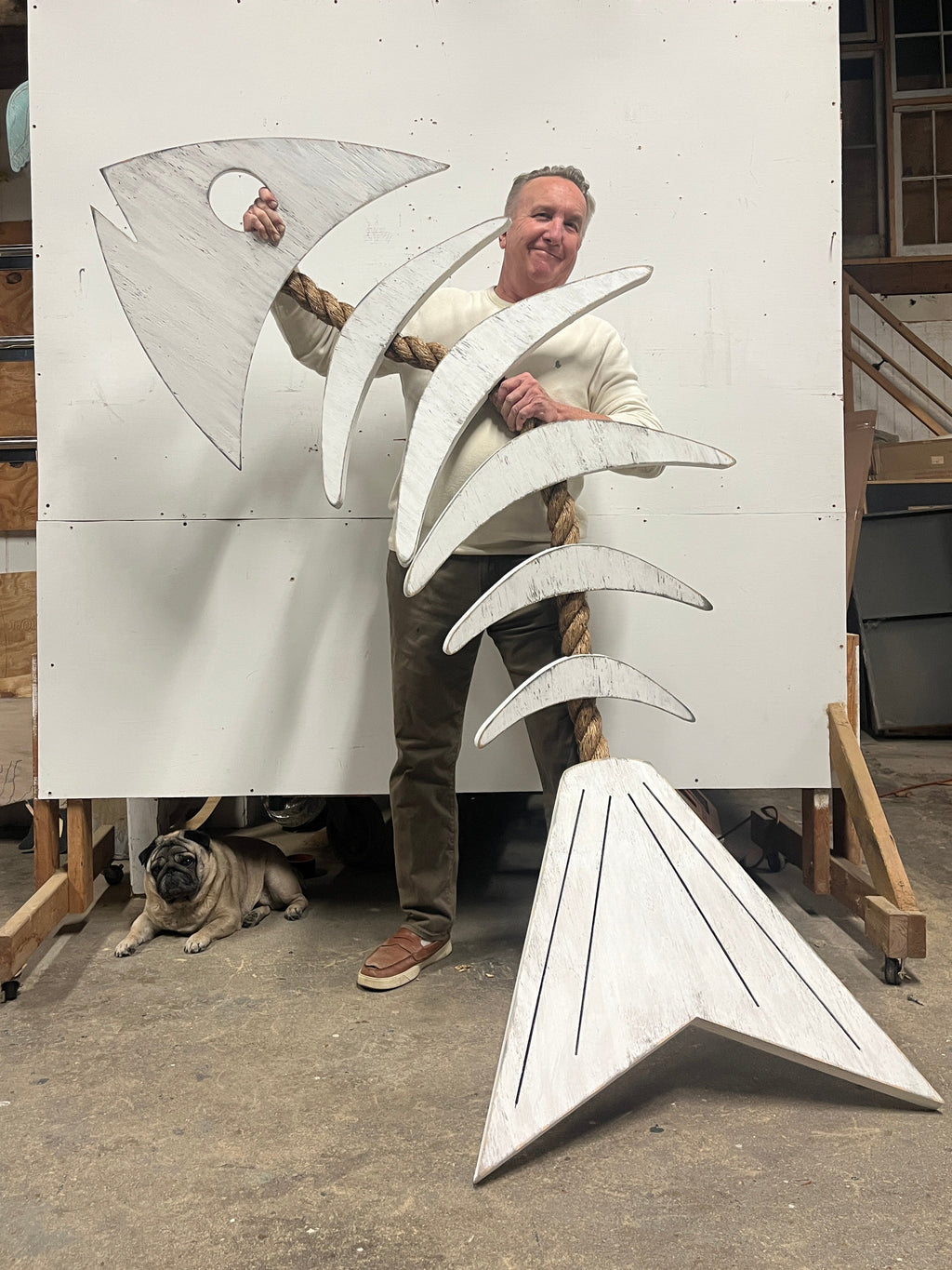 Artist gregory morris standing holding a 90" rope fish wall art in Haven America Studio