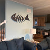 Living room with a fish bone wall art piece and kitchen in the background. 