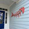 Flamingo Coral Rope Fish on a light blue house exterior with a blue door.